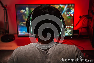 Portrait from back of teenage gamer boy looking at screen and pl Stock Photo