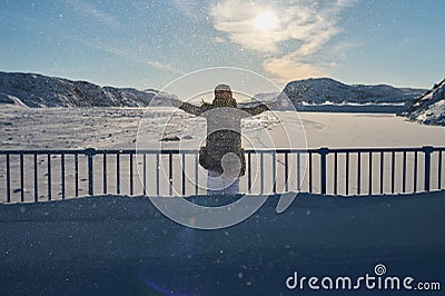 Portrait from back of warmly dressed woman in defocus standing in front of sea looking far away looking at winter rough Stock Photo
