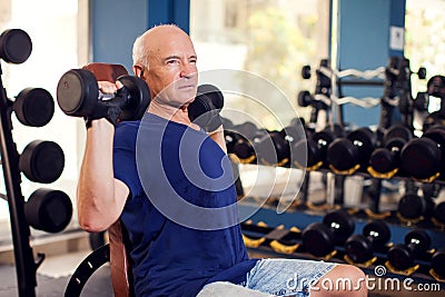 A portrait of senior man in the gym training with dumbbells. People, health and lifestyle concept Stock Photo