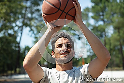 portrait basketball player taking jump shot outdoors Stock Photo