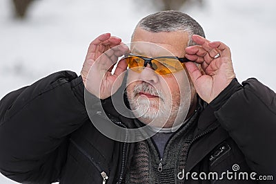 Portrait of bearded Caucasian senior man adjusting sun glasses at winter season Stock Photo