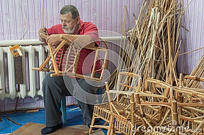 Portrait of bearded Caucasian senior master of wicker-work making kids chair Stock Photo