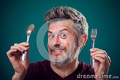 A portrait of bearded man holding spoon and fork in hands. People and food concept Stock Photo