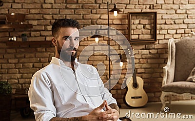 Portrait of bearded man at loft home with guitar Stock Photo