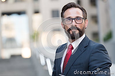 Portrait of bearded man in suit on background of building. Handsome businessman outdoor. Male business person stands on street and Stock Photo