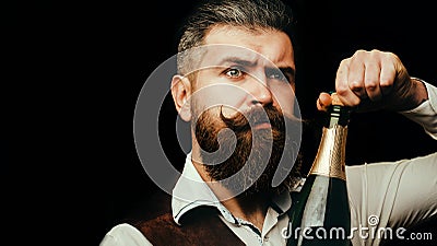 Portrait of a bearded waiter holding a champagne bottle. Close up portrait of man uncorking a bottle of champagne Stock Photo