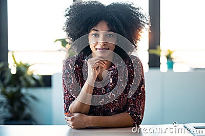 Beautiful afro young woman explaing something looking at camera while doing video call in the office Stock Photo