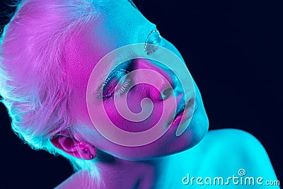 Portrait of beautiful albino girl on dark studio background in neon light Stock Photo