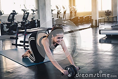 Portrait of Beautiful Asian Women is Exercising With Roller Wheel in Gym, Attractive Sporty Girl is Abdominal Exercised with Rolli Stock Photo