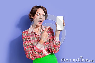 Portrait of beautiful astonished girl wear shirt indicating at eshop on smartphone display empty space isolated on blue Stock Photo