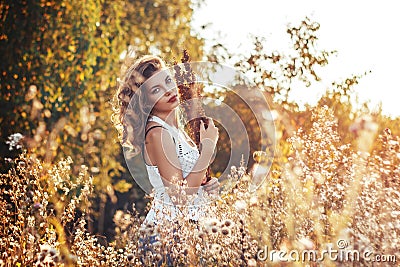 Young woman with a flowers in autumn field Stock Photo