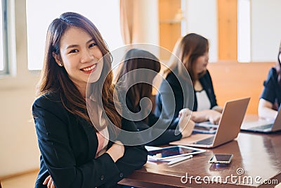 Portrait of a beautiful authentic satisfied business woman looking at camera with team at behind. Concept for leadership and succe Stock Photo