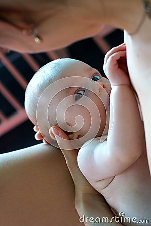 Beautiful baby breastfeeding close up, mom is holding little infant in the arms and feeding her with mother`s breast milk Stock Photo