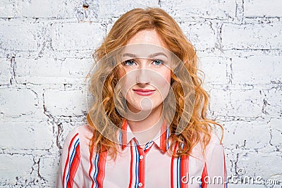 Portrait of a beautiful beautiful young woman student with red curly hair and freckles on her face is leaning against a brick wall Stock Photo