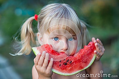 Portrait of beautiful blonde little girl with two ponytails eating watermelon Stock Photo