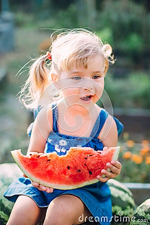 Portrait of beautiful blonde little girl with two ponytails eating watermelon Stock Photo