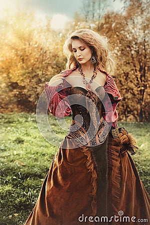 Portrait of a beautiful blonde woman in a historical costume in nature, Stock Photo