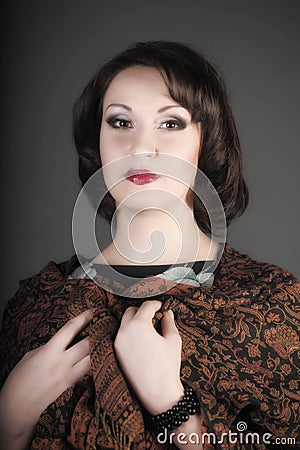 Portrait of a beautiful brunette woman with a brown scarf with a pattern on her shoulders in a studio Stock Photo