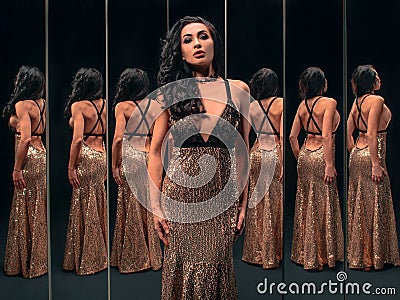 Portrait of beautiful brunette woman in golden dress near the mirrors Stock Photo