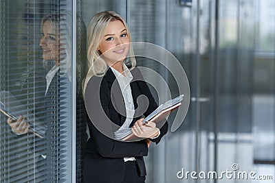 Portrait of beautiful businesswoman smiling and standing with folder in the office Stock Photo