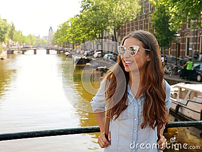 Portrait of beautiful cheerful girl with sunglasses looking to the side on one of typical Amsterdam channels, Netherlands Stock Photo