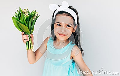 Portrait of the beautiful child holds the bouquet of white flowers for her mother. Cute kid smiling and holds a bouquet on white Stock Photo