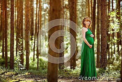 Portrait of a beautiful curly haired pregnant girl in the green Stock Photo