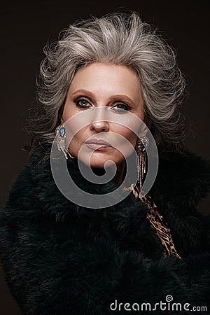 Portrait of a beautiful elderly woman in a leopard blouse and fur coat with classic makeup and gray hair. Stock Photo
