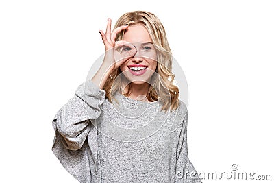 Portrait of beautiful excited woman in casual clothing smiling and showing ok sign at camera isolated over white. Stock Photo