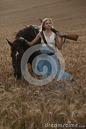 Portrait of a beautiful female cowgirl with shotgun from wild west riding a horse in the outback. Stock Photo