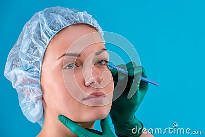 Portrait of a beautiful girl close-up, with smooth skin, hands holding a scalpel in the face with gloves. Concept beauty Stock Photo