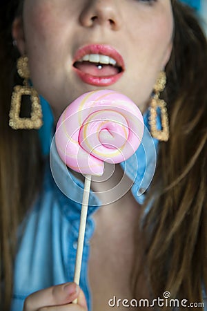 Portrait of a beautiful girl with colorful pink twirl lollipop hard candy on blue background, sweets,sugar unhealthy Stock Photo