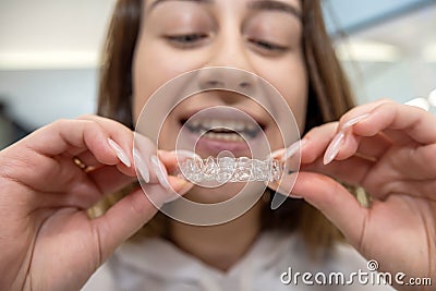 Portrait of beautiful girl patient holding orthodontic retainers aligners in dental clinic. Stock Photo