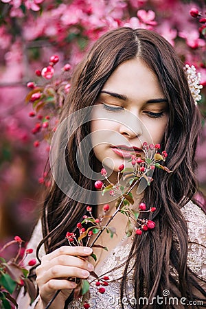 Portrait of beautiful girl in a pink dress, looking down with half open lips, keeps on hand a twig with buds, close-up Stock Photo