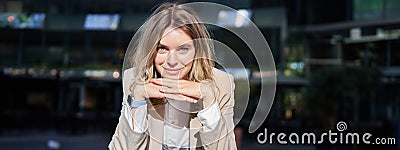 Portrait of beautiful happy corporate woman in suit, stands on street and smiles, poses near office buildings Stock Photo