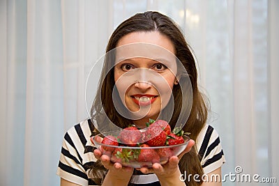 Portrait of a beautiful happy woman in the window with strawberries. Beauty youth happiness Stock Photo