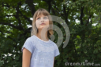 Portrait of a beautiful liitle girl close-up on a background of green leaves Stock Photo