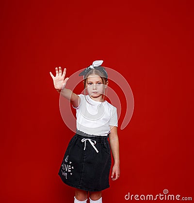 Portrait of a beautiful little girl posing on an isolated red background. extend your arm forward stop Stock Photo