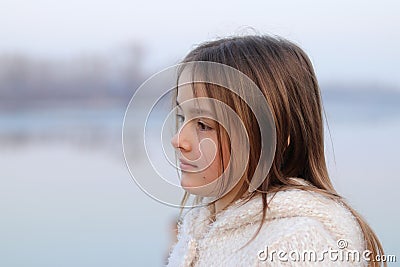 Portrait of beautiful little girl in white coat looking thoughtfully on the left Stock Photo