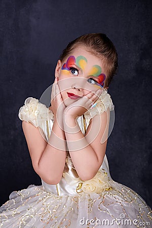 Portrait of Beautiful little girl in white dress red lips with painted face at dark background. Stock Photo