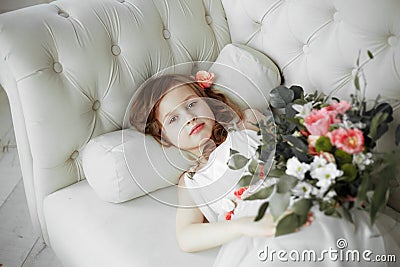 Portrait of beautiful little girl in white dress on white sofa Stock Photo