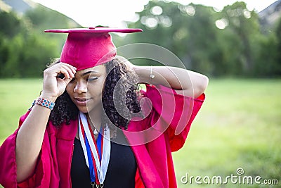 Portrait of a beautiful multiethnic woman putting on her graduation cap and gown Stock Photo