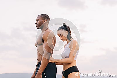 Portrait of beautiful muscular mixed race couple with perfect bodies in sportswear softly embracing on mountains Stock Photo