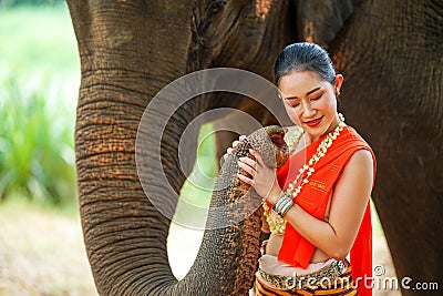 Portrait of Beautiful rural Thai woman wear Thai northern traditional dress for phot shoot with trunk of Asian elephant on blurred Stock Photo