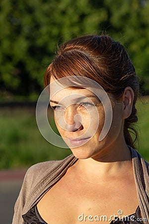 Portrait of beautiful serious middle-aged woman with calm face looking aside in summer green park Stock Photo