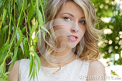 Portrait of a beautiful girl with big full lips, with white hair in a white dress near a tree Stock Photo