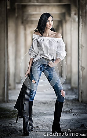 Portrait of beautiful young woman with modern outfit, leather jacket, jeans, white blouse and black boots Stock Photo