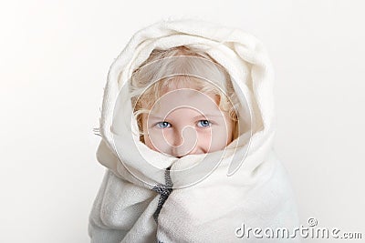 Portrait of beautiful smiling Caucasian girl wrapped in white blanket. Happy preschool child with blue eyes covered with warm Stock Photo