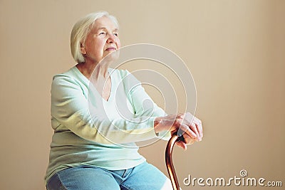 Portrait of beautiful smiling senior woman with walking cane on light background at home Stock Photo