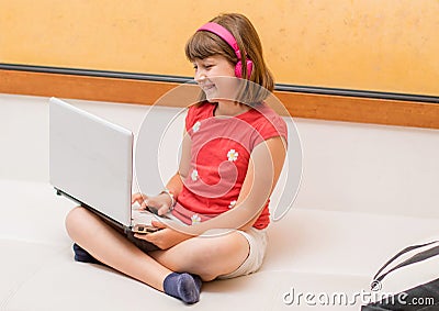 Portrait of a beautiful student viewing and listening video tutorials on line with headphones Stock Photo